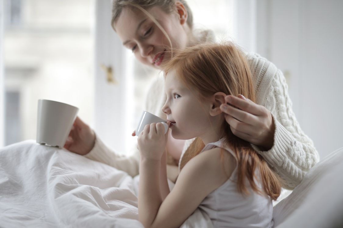 Mother comforting child with warm tea during cold and flu season